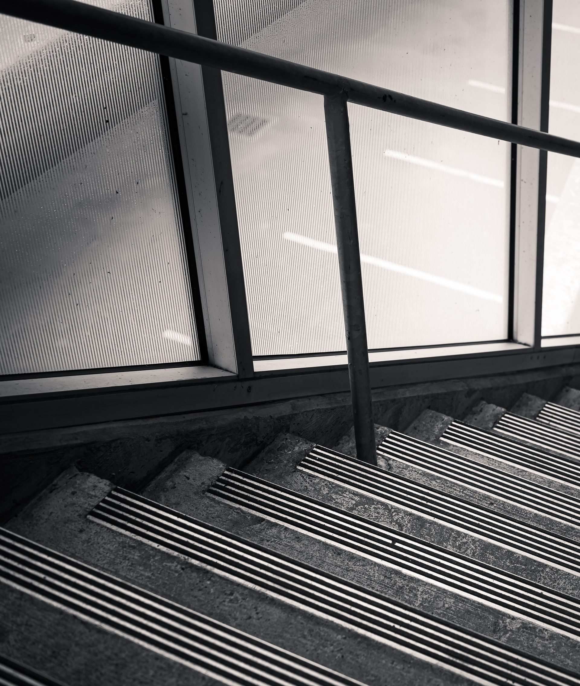 Monochrome image of a staircase with anti-slip strips and handrail, providing safety.