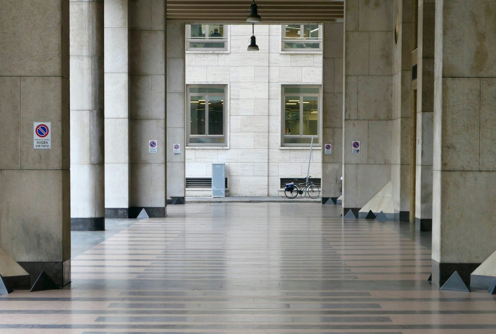 Long architectural corridor with hanging lights and patterned floor.